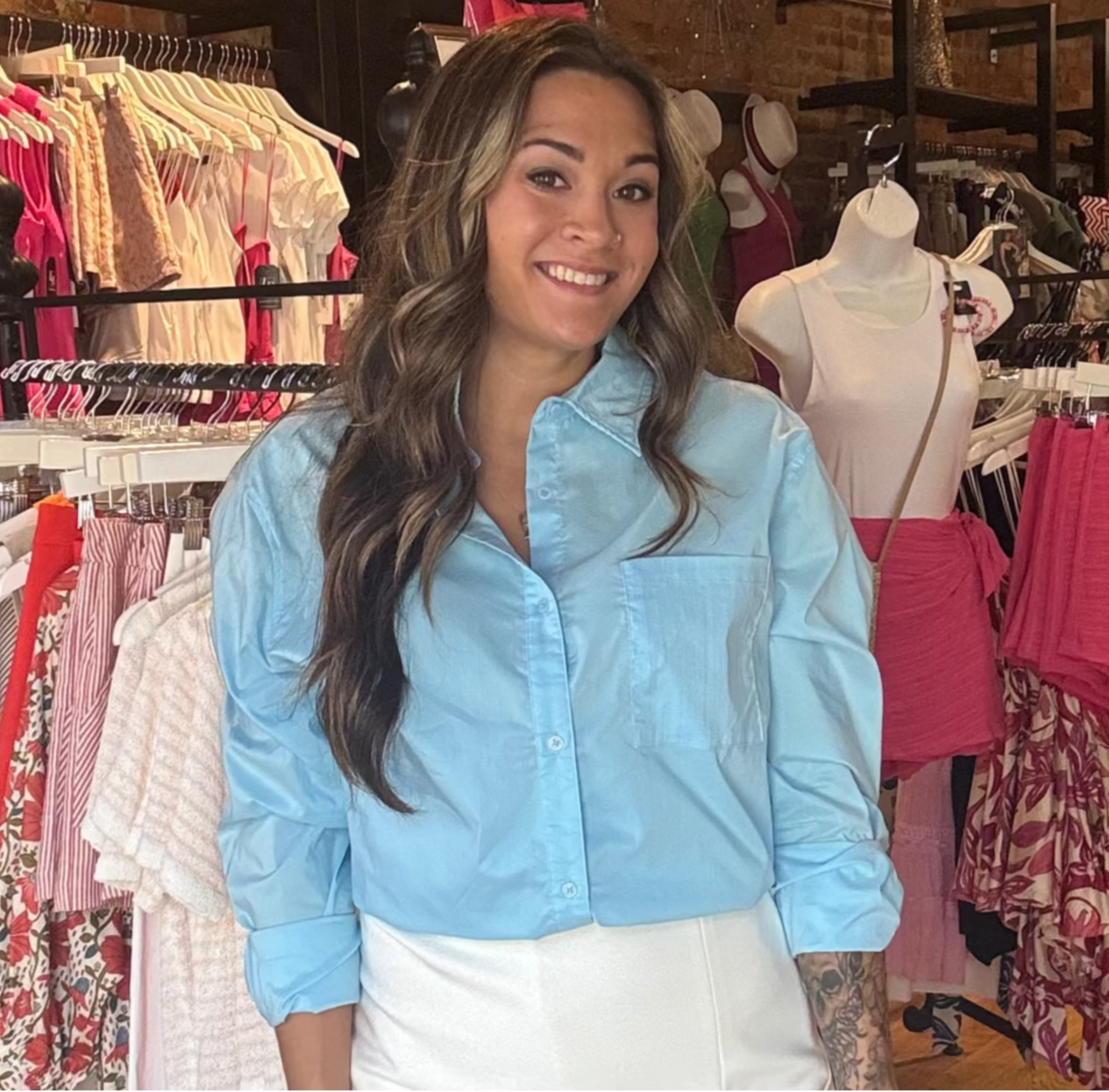 Woman standing in a clothing store with racks of clothes in the background