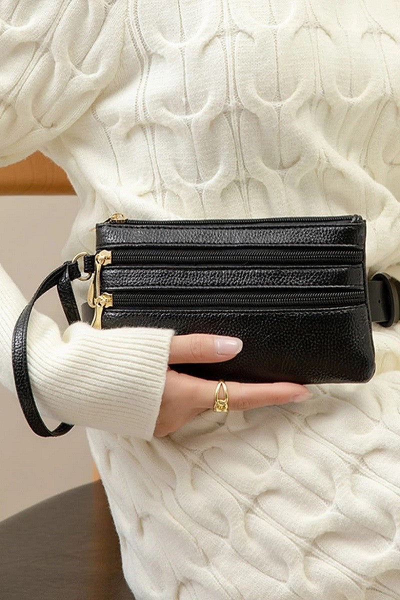 Black wristlet held by a person wearing a white sweater