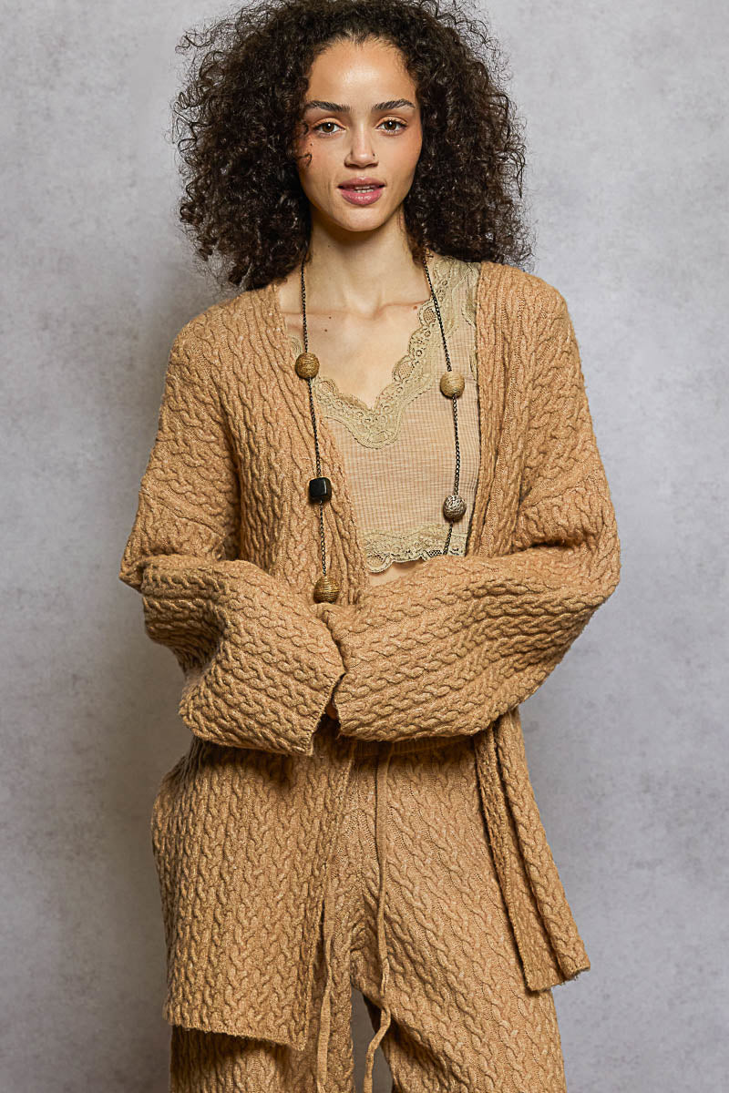 Woman wearing a brown textured cardigan against a gray background