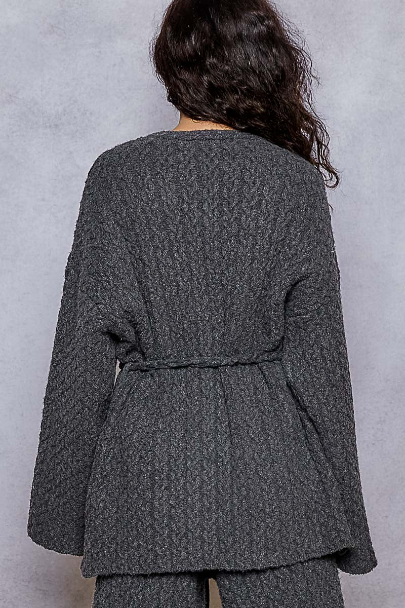 Person wearing a textured gray coat against a plain background