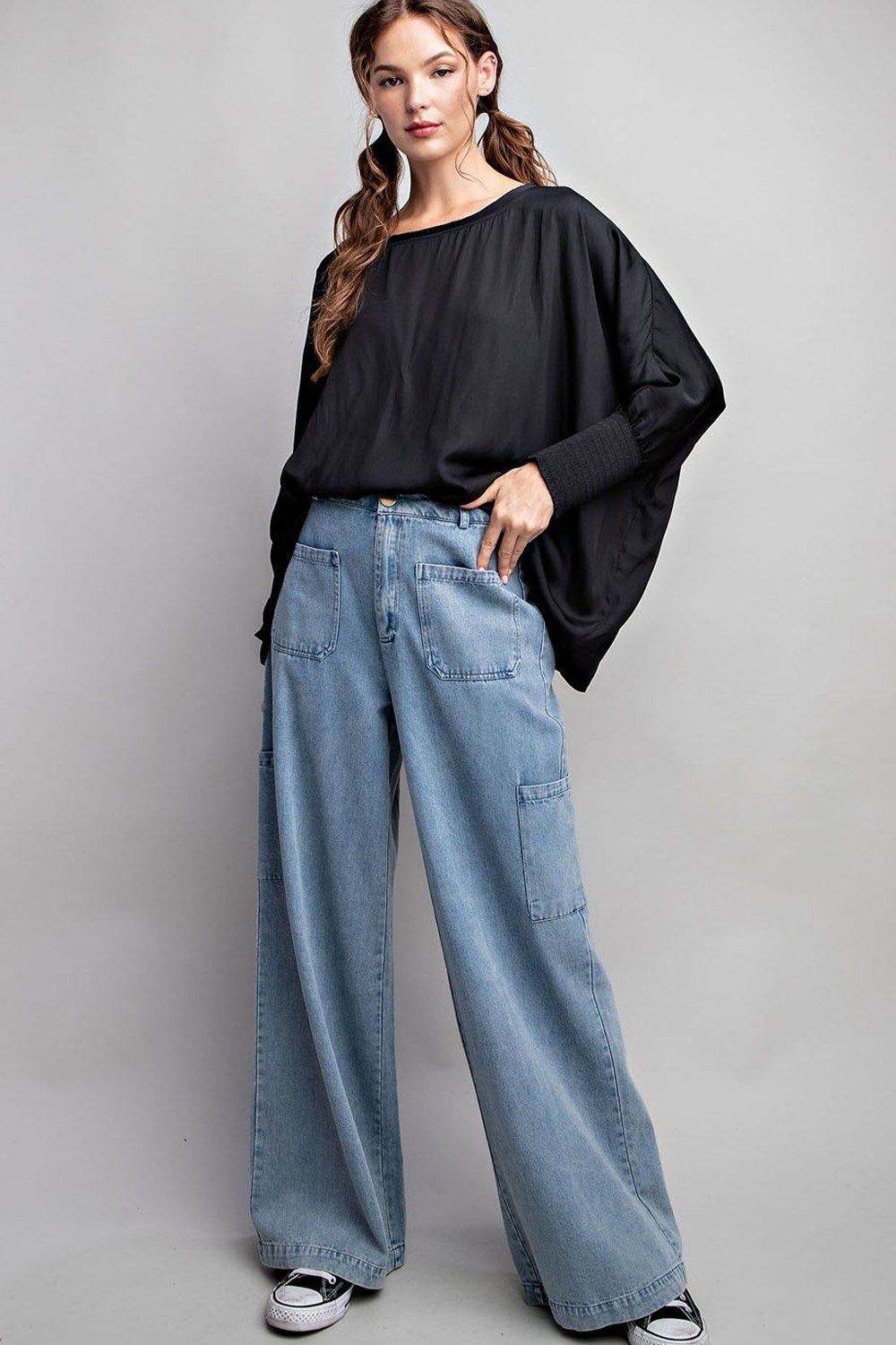 Woman wearing a black top and blue jeans on a gray background