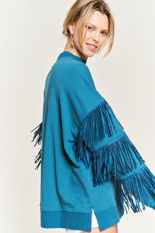 Teal fringe sweater worn by a person on a plain background