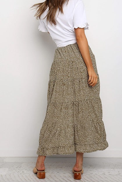 Person wearing a white top and patterned skirt against a plain background