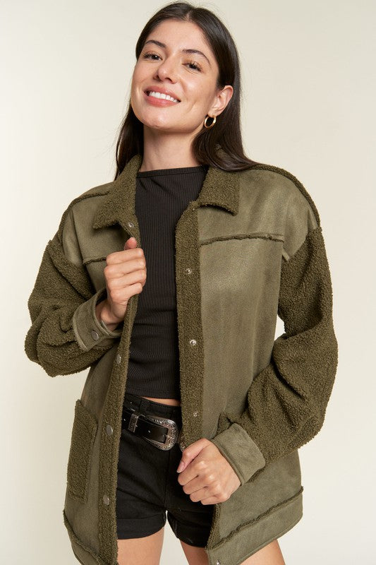 Woman wearing an olive green jacket against a plain background