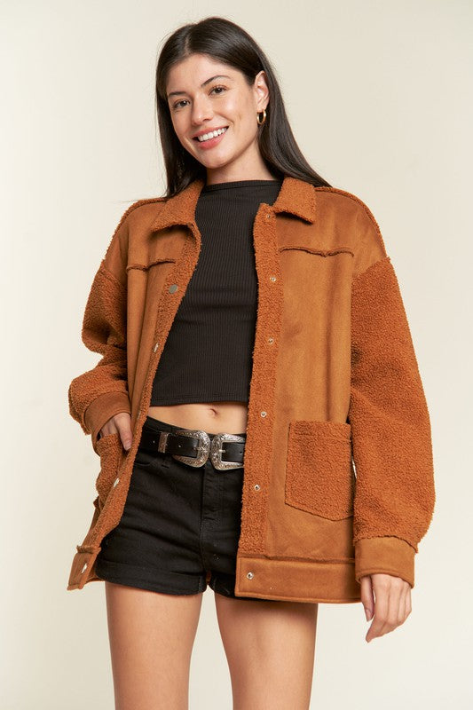 Woman wearing a brown jacket over a black top and shorts on a beige background