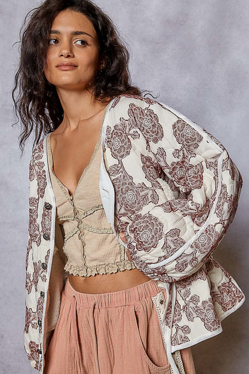 Woman wearing a floral kimono-style garment against a gray background