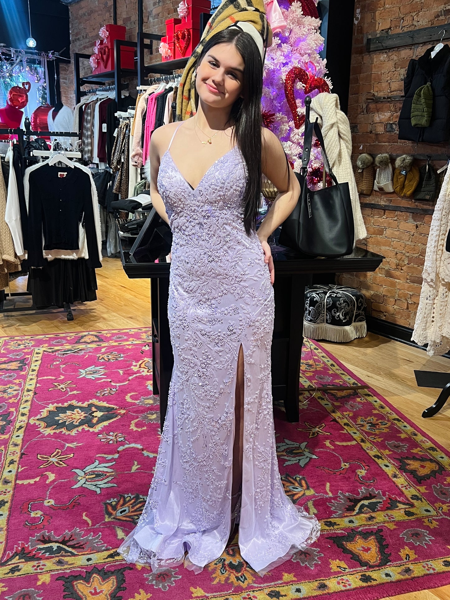 Woman in a white lace evening gown standing in a clothing store with colorful decorations.