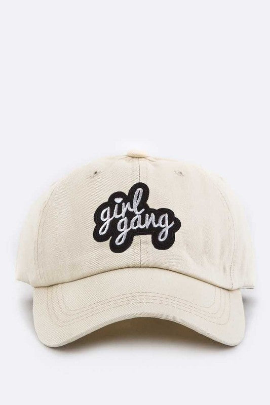 Beige cap with 'girl gang' text on a white background