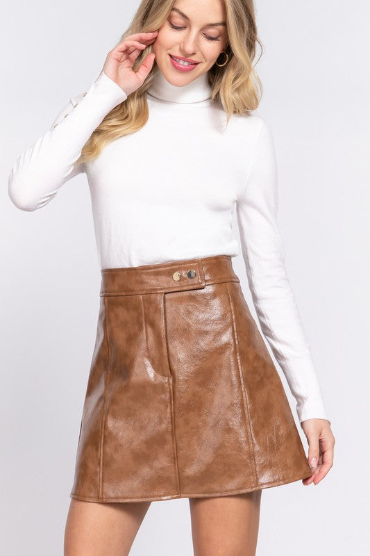 Woman wearing a white turtleneck and brown leather skirt on a white background