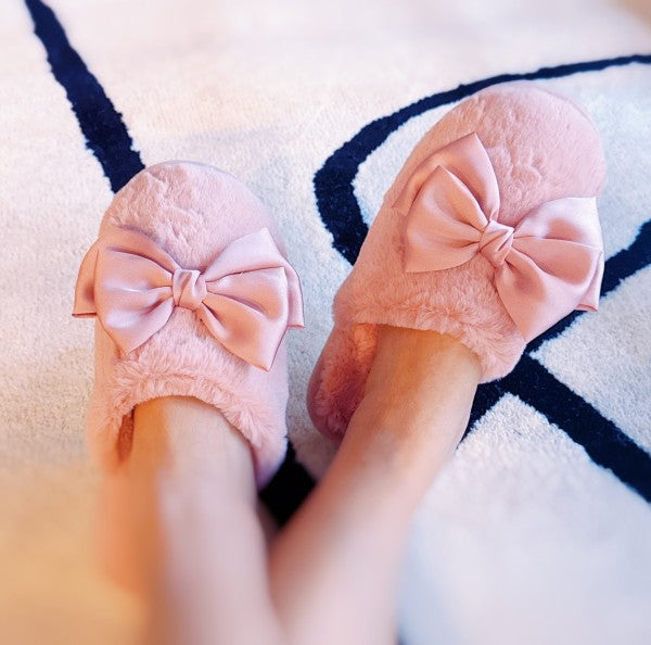 Pink slippers with bow details on a patterned rug