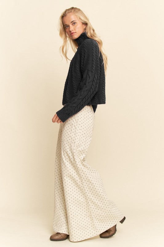Woman wearing a dark sweater and patterned skirt on a beige background