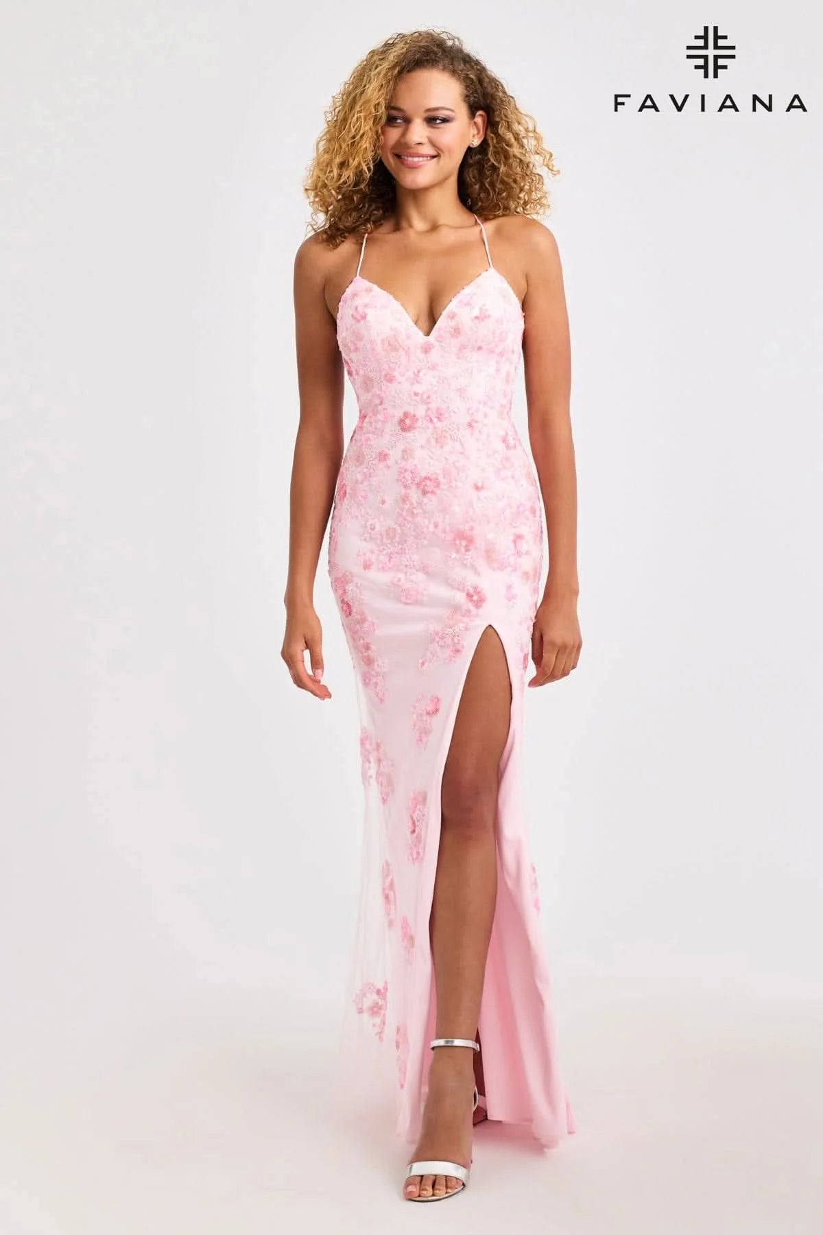 Woman wearing a pink floral dress with a high slit on a white background, branded 'Faviana'.