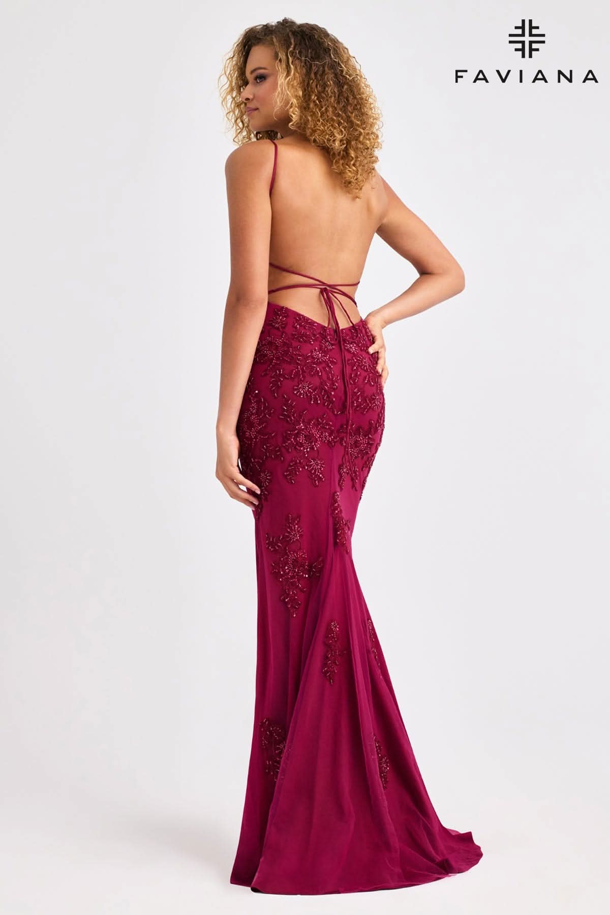 Woman wearing a burgundy evening gown with lace details, standing against a white background. Brand 'Faviana' visible.