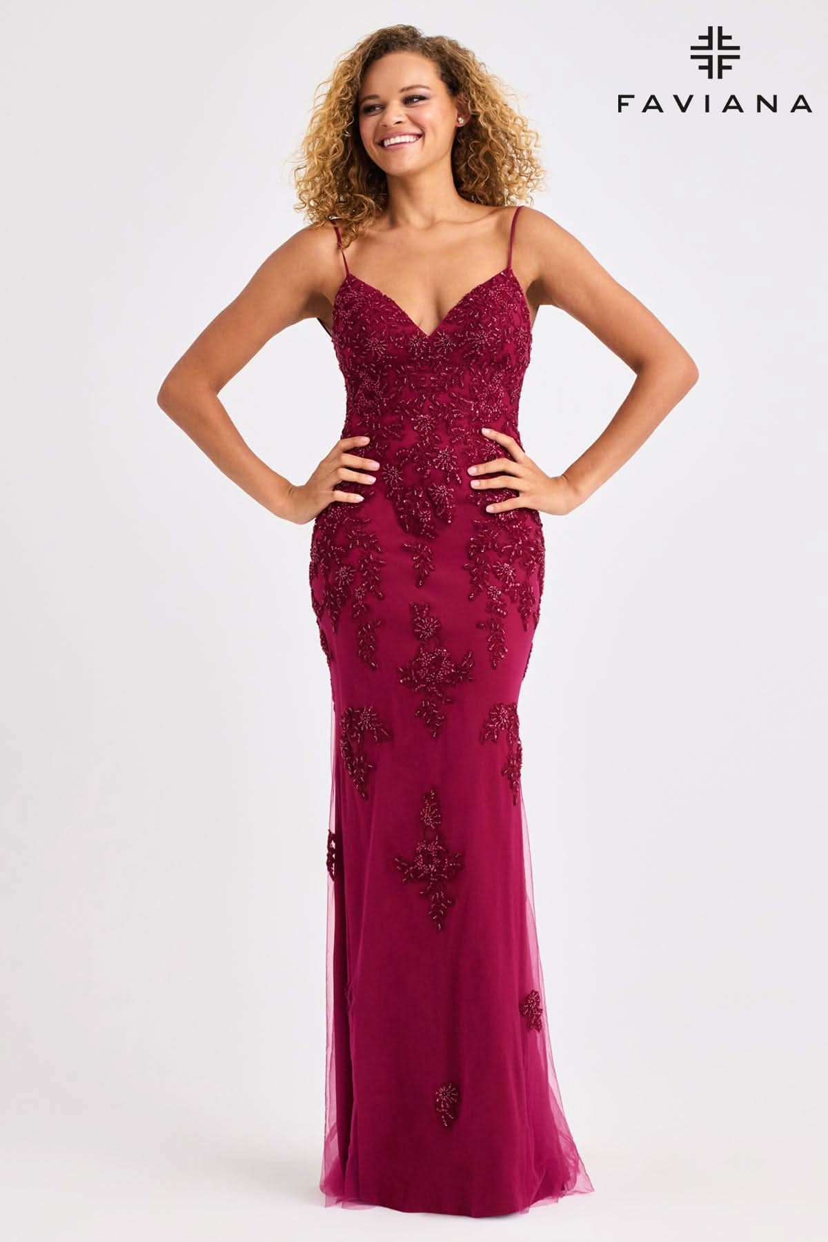 Woman wearing a burgundy evening gown with floral embellishments on a white background, branded 'Faviana'.