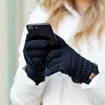 Person wearing gloves holding a phone with a blurred background