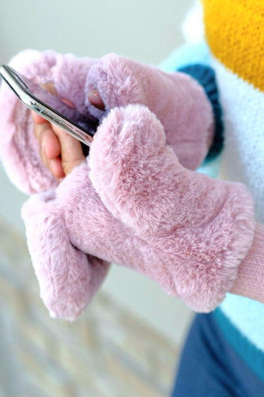 Pink fuzzy gloves holding a smartphone with a blurred background