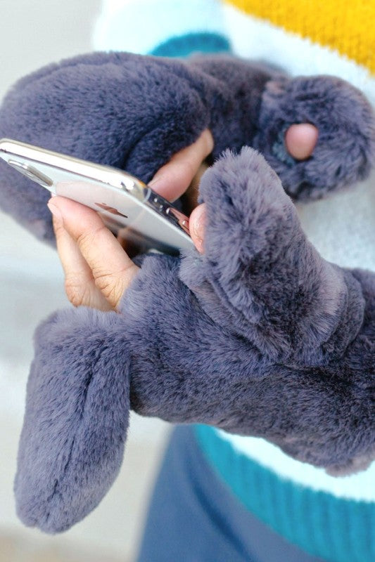 Person wearing gray fuzzy gloves using a smartphone.