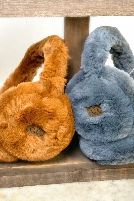 Pair of orange and blue fuzzy earmuffs on a wooden surface.