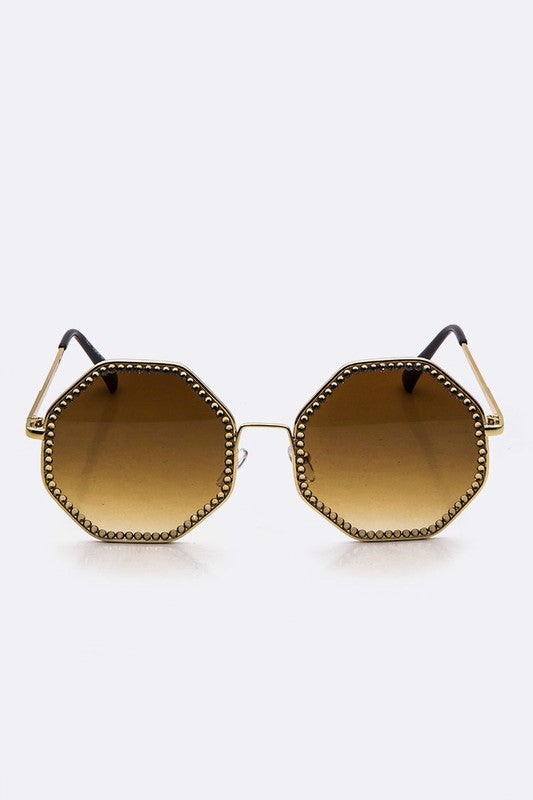Hexagonal sunglasses with gold frame and brown gradient lenses on a white background