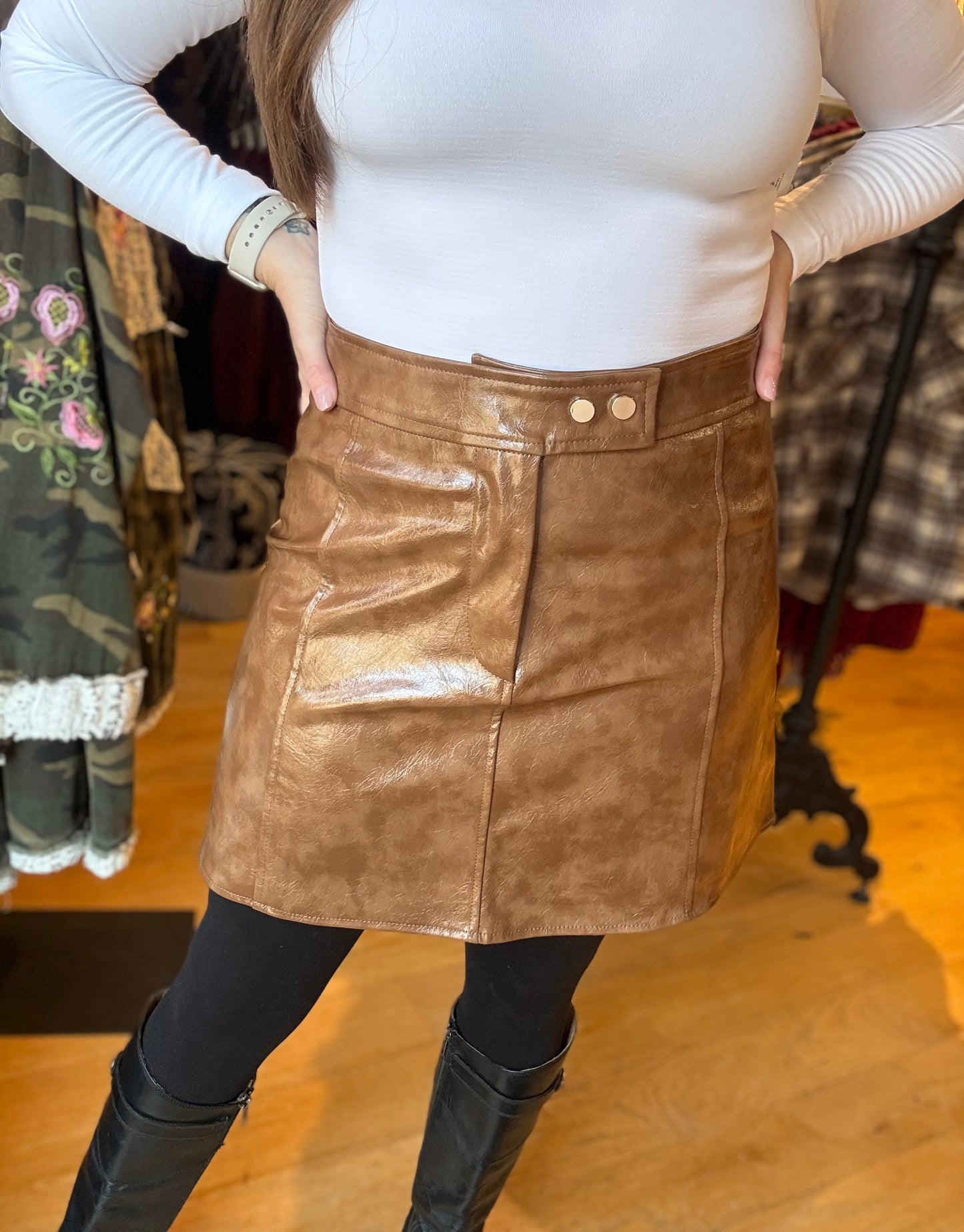 Person wearing a brown leather skirt with a white top in a clothing store.