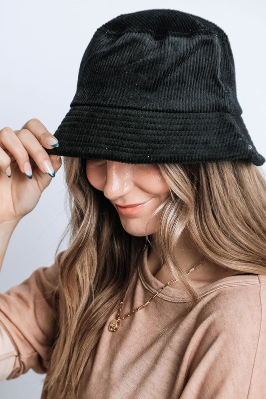 Person wearing a black bucket hat with a plain background