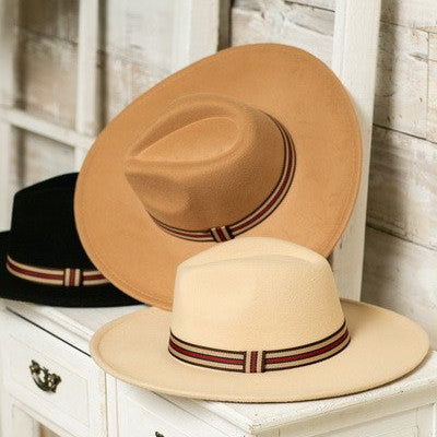 Two hats, one beige and one brown, with a striped band, on a white surface.