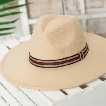 Beige wide-brimmed hat with a striped band on a white surface