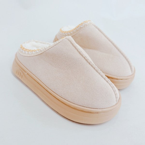 Pair of beige slippers on a light gray background