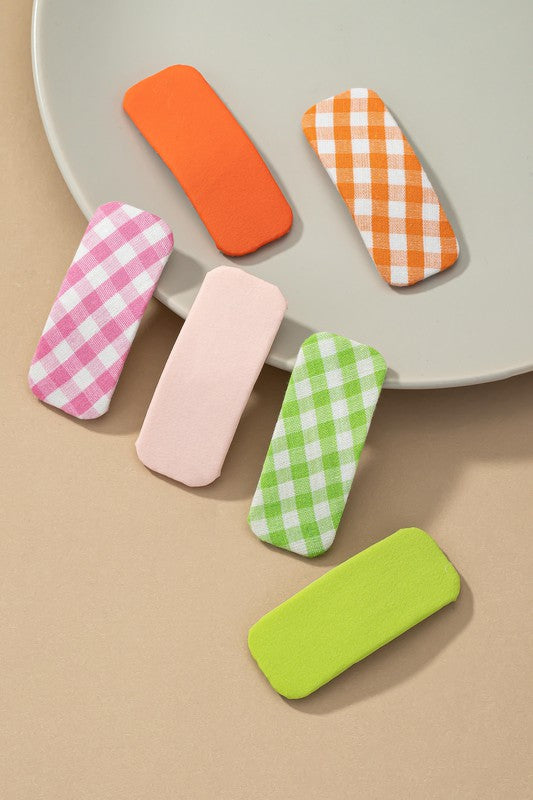 Colorful gingham-patterned hair clips on a beige background