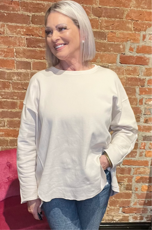 Woman wearing a cream-colored long sleeve pullover sweater