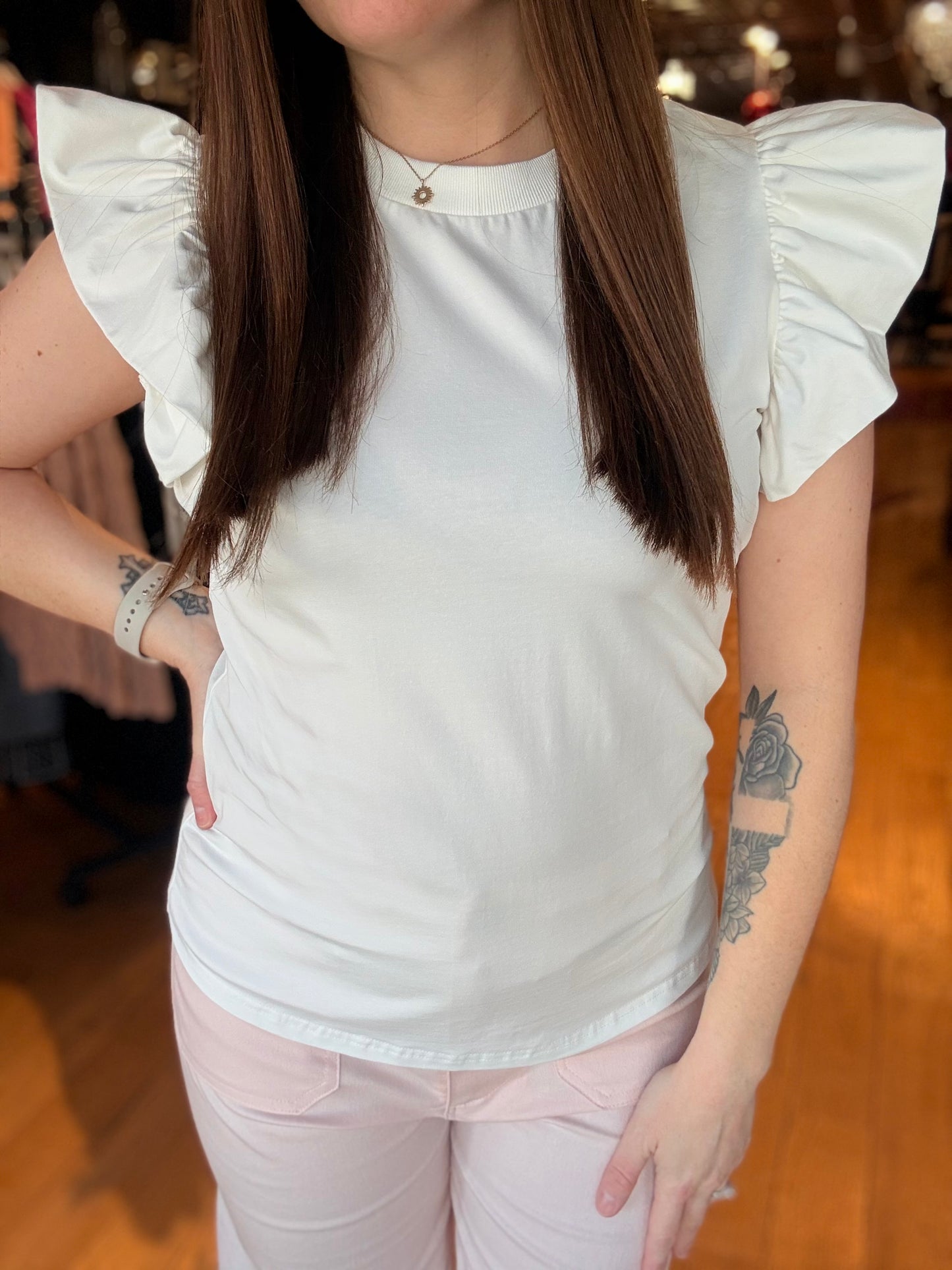 Person wearing a white blouse with ruffled sleeves in an indoor setting