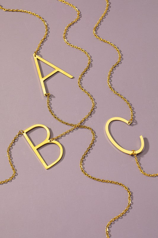 Gold necklace with 'A', 'B', and 'C' letters on a purple background