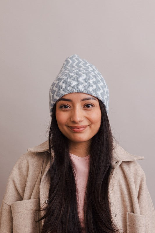Woman wearing a blue patterned beanie against a plain background