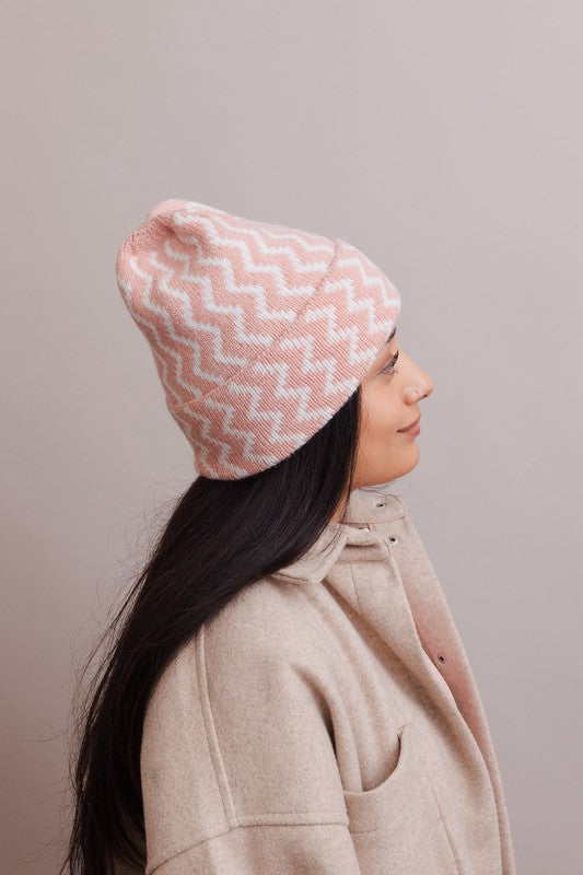 Person wearing a pink and white patterned knit hat against a plain background