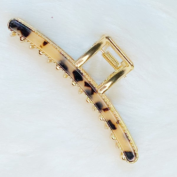 Gold hair clip with tortoiseshell pattern on a white background