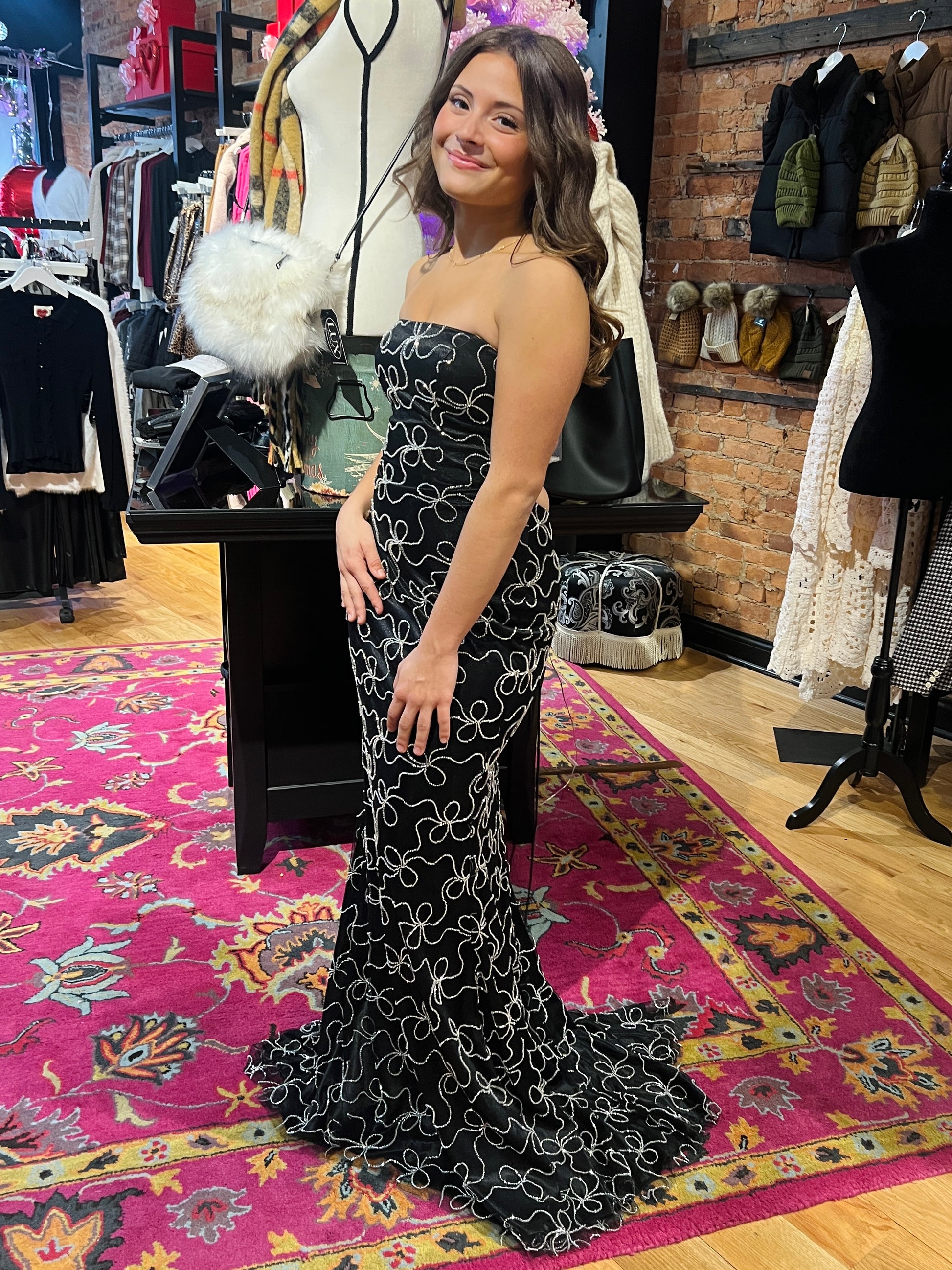 Woman in a strapless black and white patterned dress standing in a clothing store.
