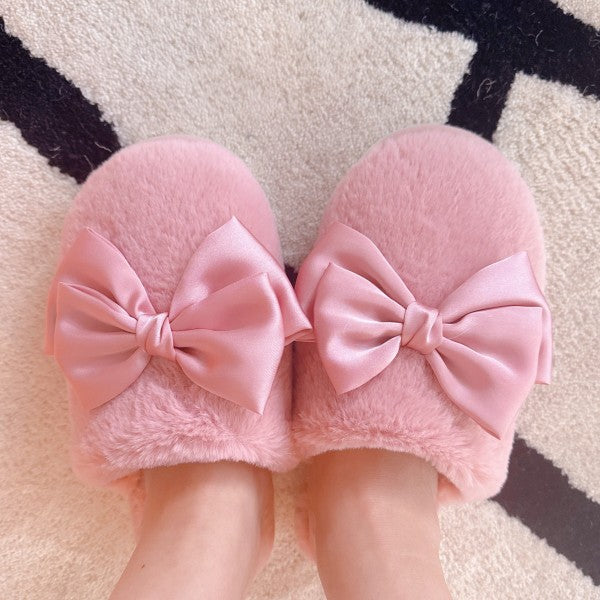 Pink slippers with large bows on a patterned rug