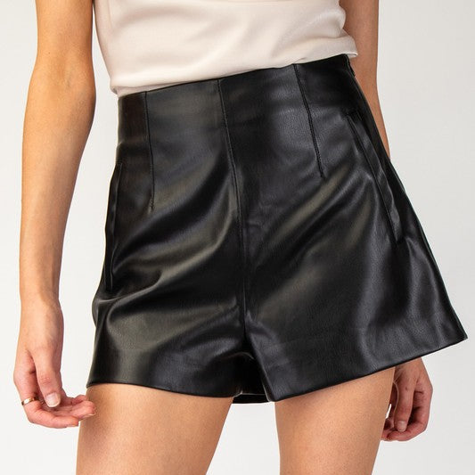 Black leather shorts worn by a person on a white background