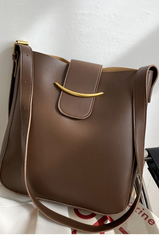 Brown leather handbag with a gold buckle on a white surface