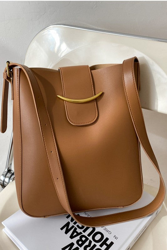 Brown leather handbag with a gold buckle on a white surface