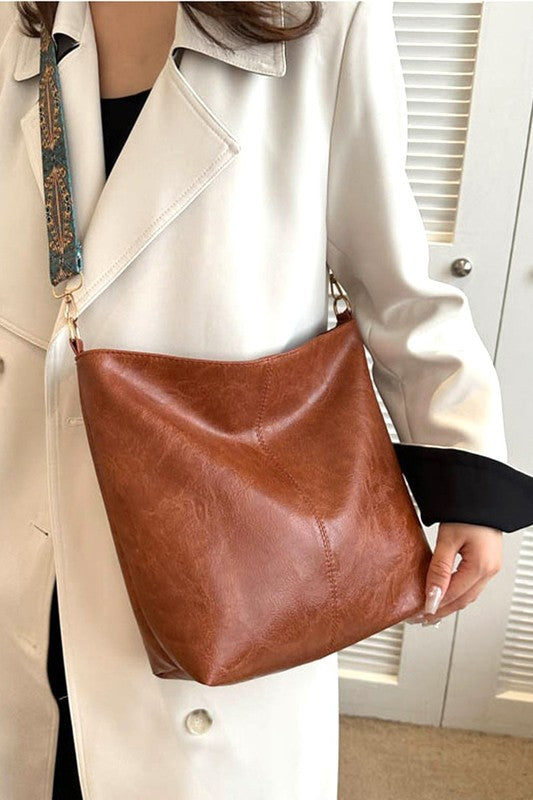 Person holding a brown leather bag with a neutral background