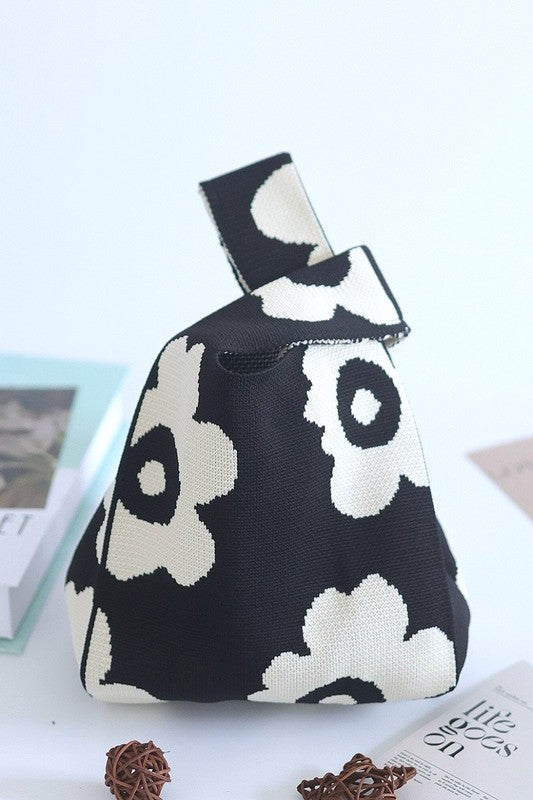 Black and white patterned bag on a light surface with books and decorative items.