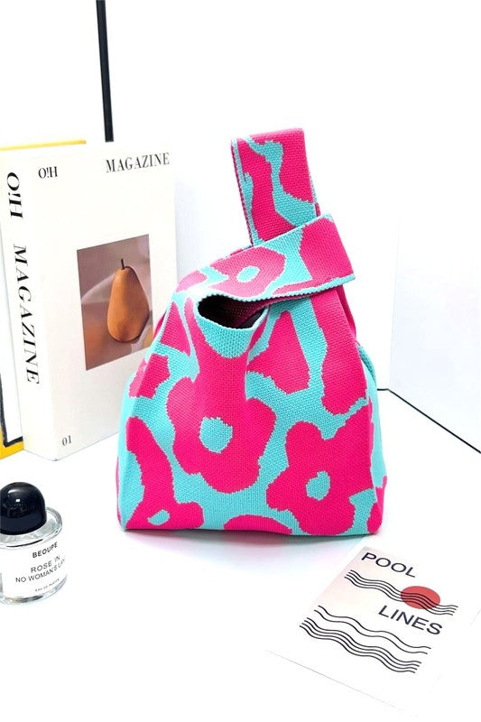 Floral-patterned handbag on a white surface with a magazine and nail polish bottle in the background.