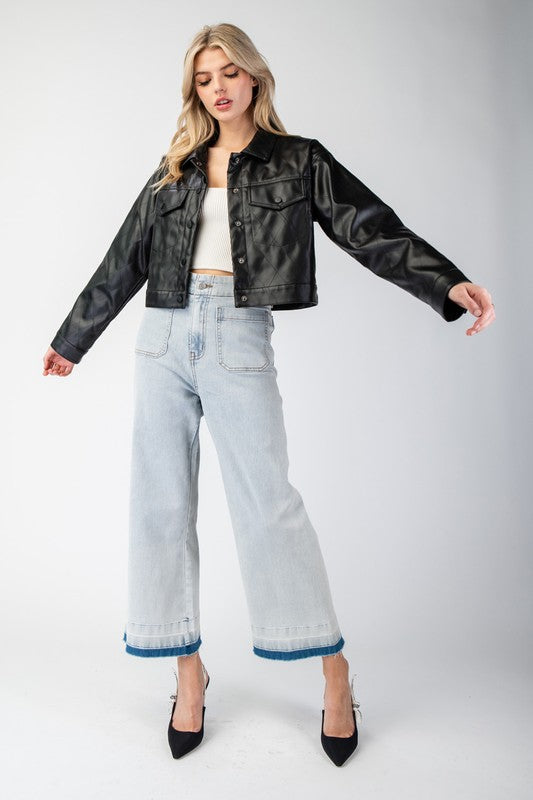 Woman wearing a black leather jacket, white top, and light blue jeans on a white background