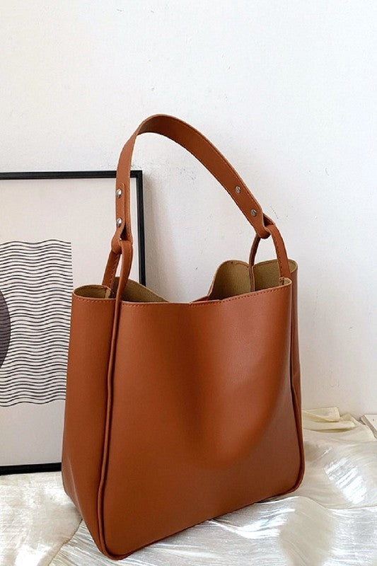 Brown leather handbag on a light surface with a white background