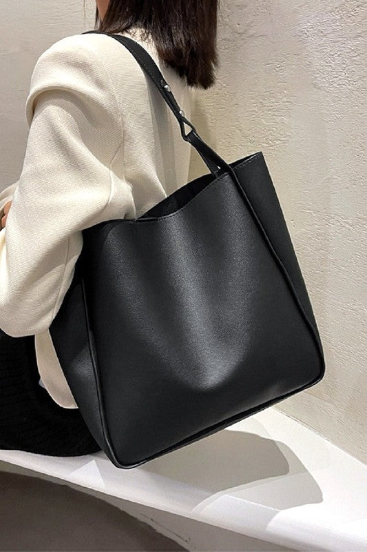 Person holding a black handbag against a neutral background