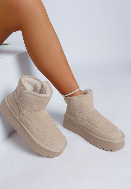 Beige winter boots worn by a person on a white background