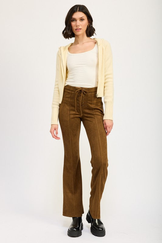 Woman wearing a cream top, yellow cardigan, and brown corduroy pants on a white background