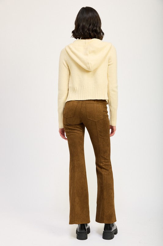 Person wearing a light yellow sweater and brown corduroy pants on a white background