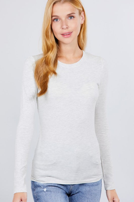 Woman wearing a white long-sleeve top and blue jeans on a light gray background